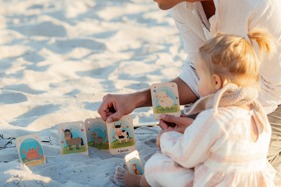 Papa und Tochter spielen mit Lernkarten am Strand