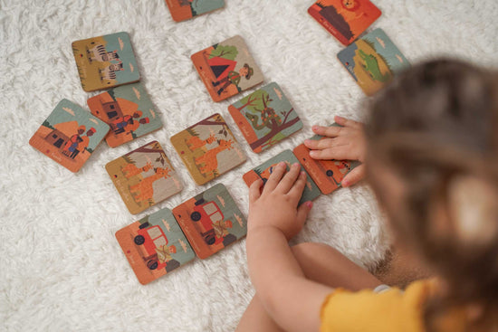 Kind spielt mit Memospielkarten Memorykarten Memokarten aus Holz Safari Abenteuer Motive auf den Holzkarten abgebildet.