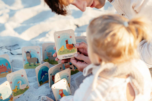 kind spielt mit montessori lernkarten als spielzeug am strand mit ihrem Vater