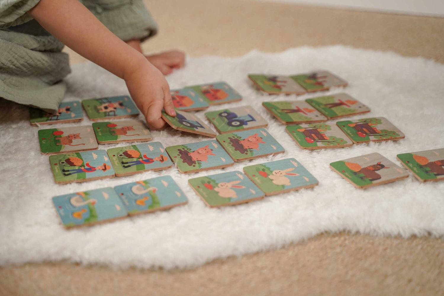 Kind spielt mit Memorykarten aus Holz Bauerhof Figuren