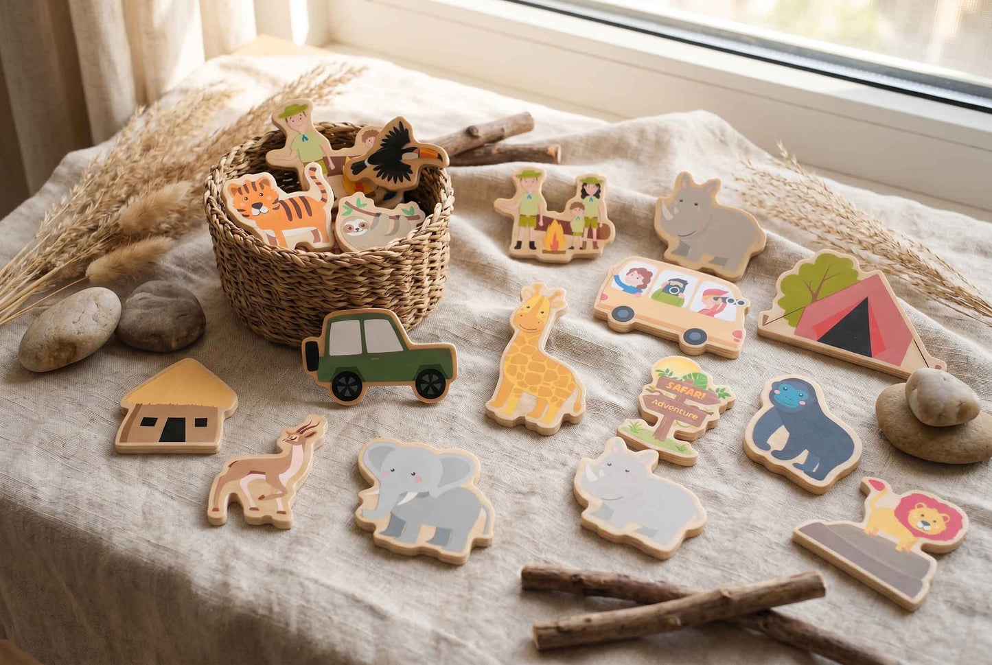 Holzspielzeug mit Safari- und Camping-Motiven. Enthält einen Tiger, eine Giraffe, ein Nashorn, einen Elefanten und einen grünen Jeep. Ein Bus mit Passagieren, ein Zelt und ein Schild sind ebenfalls vorhanden. Das Spielzeug befindet sich in einem Weidenkorb.