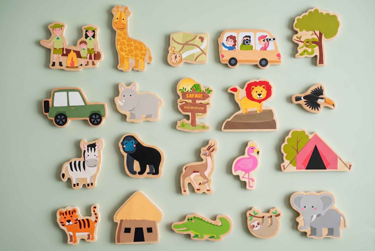 Holzspielzeug-Set zum Thema Safari mit verschiedenen Tieren, einem Safari-Bus und einem Campingplatz. Das Set enthält eine Giraffe, einen Löwen, ein Zebra und andere Tiere in leuchtenden Farben, angeordnet auf einem hellgrünen Hintergrund.